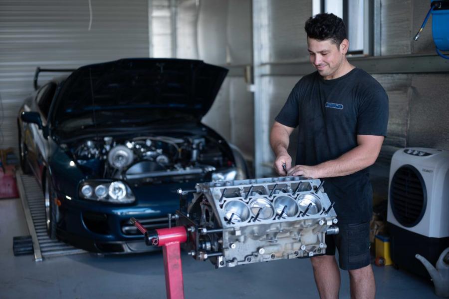 Engine block on a stand beside a car