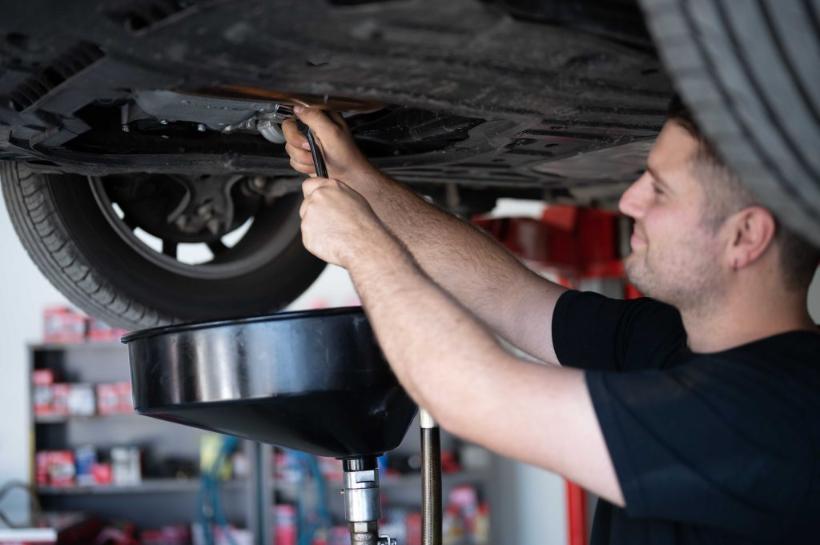 Mechanic draining oil from a car on the hoist